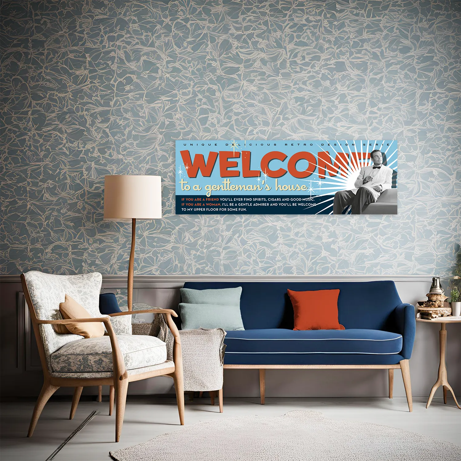 Pann.Welcome_Vincent-amb-divano Foto ambientata in casa che mostra su parete sopra il divano il Pannello decorativo Pannello decorativo azzurro Bachelor Signboard stile retrò anni ’50 versione con mezzobusto di Vincent in bianco e nero e scritta 'Welcome' a stampatello in rosso