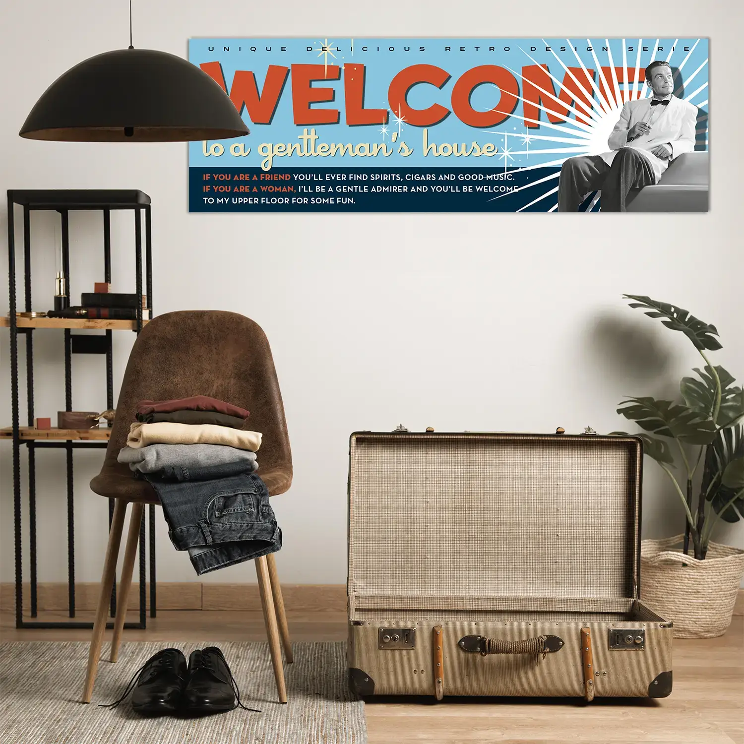 Pann.Welcome_Vincent_amb-valigia Foto ambientata in casa che mostra su parete il Pannello decorativo Pannello decorativo azzurro Bachelor Signboard stile retrò anni ’50 versione con mezzobusto di Vincent in bianco e nero e scritta 'Welcome' a stampatello in rosso