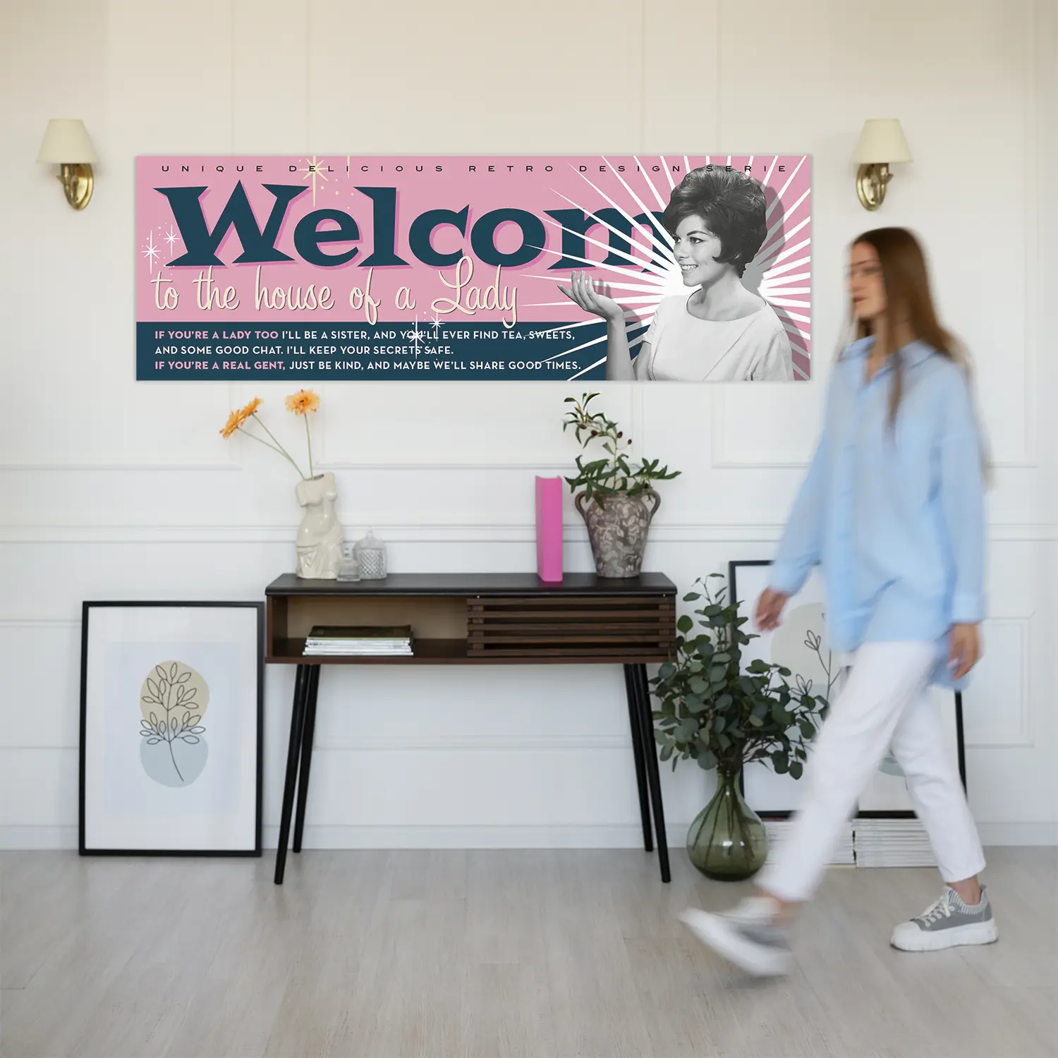 pannello Welcome Connie ambientazione Foto ambientata in casa che mostra su parete il Pannello decorativo Maiden Signboard vintage anni ’50 dallo sfondo rosa, scritta 'Welcome' in blu e icona femminile di Connie in bianco e nero