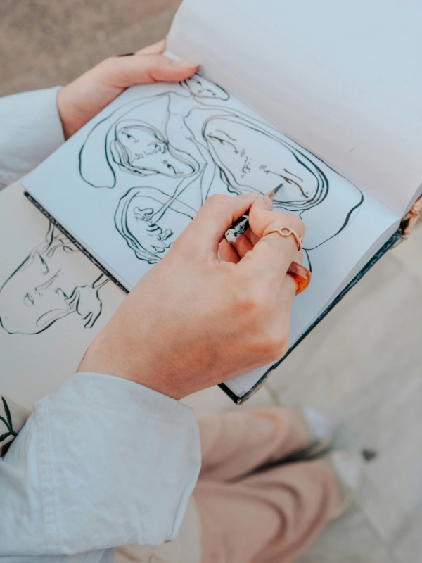 Dettaglio fotografico di un illustratrice che disegna a matita su un quaderno