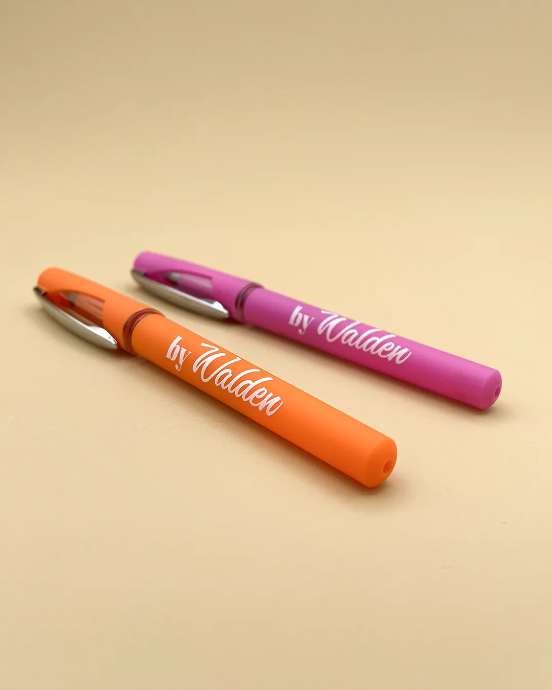 Due penne gel di colore fucsia e arancio, con logo bianco 'byWalden', tappo protettivo con finestrella trasparente e clip metallica per aggancio