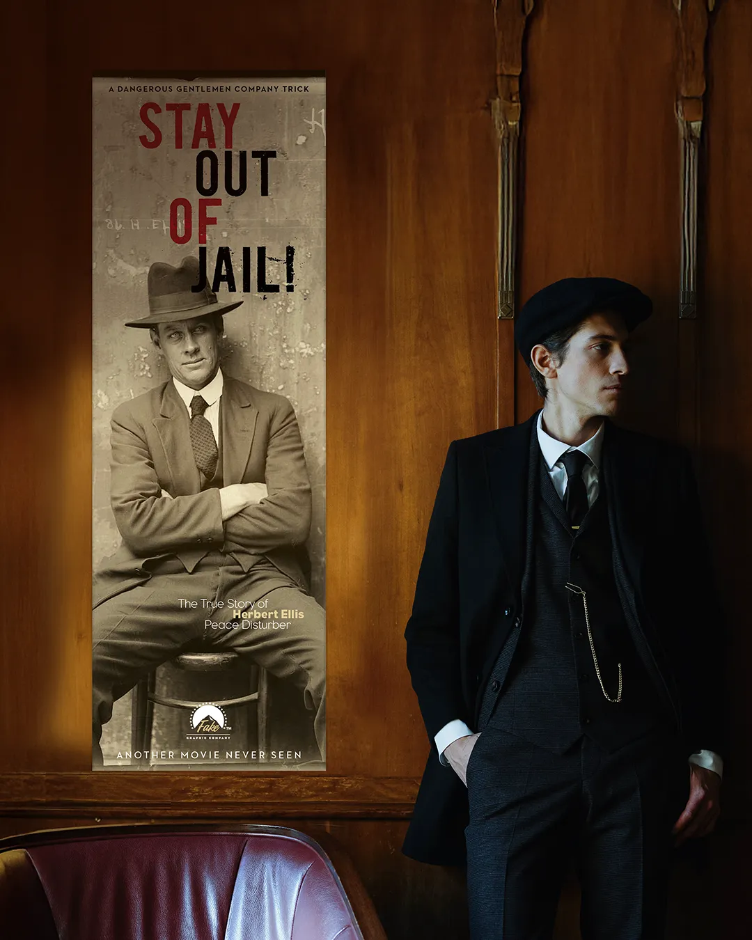 Uomo in eleganti abiti scuri con cappello nero, appoggiato a una parete in legno, accanto a un poster verticale in bianco e nero che mostra un uomo seduto e la scritta “STAY OUT OF JAIL!”.